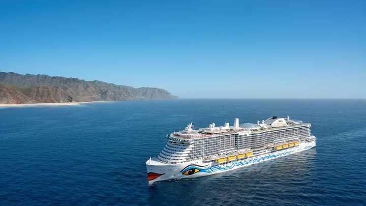 Kreuzfahrtschiff von AIDA Cruises auf dem Meer mit einer bergigen Küste im Hintergrund
